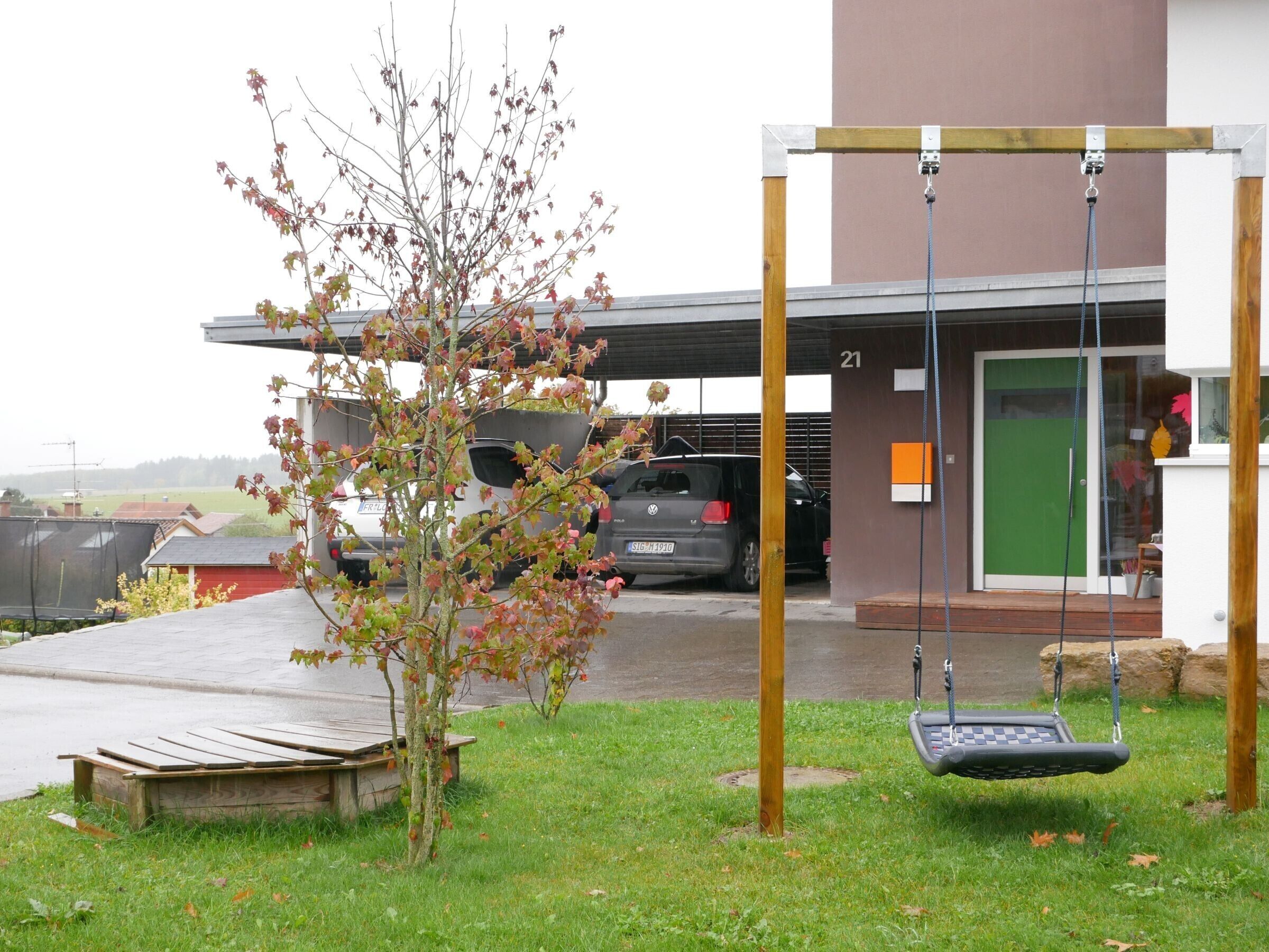 A building with a green door, a swing set, and parked cars.