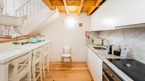 A compact kitchen with wooden beams, a white countertop, a sink, a stove, and a microwave.