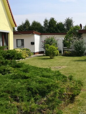 A residential building with a well-maintained lawn, a small garden, and a visible mailbox.