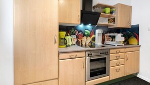 A kitchen with wooden cabinets, a stainless steel oven, and a countertop with various kitchen items.
