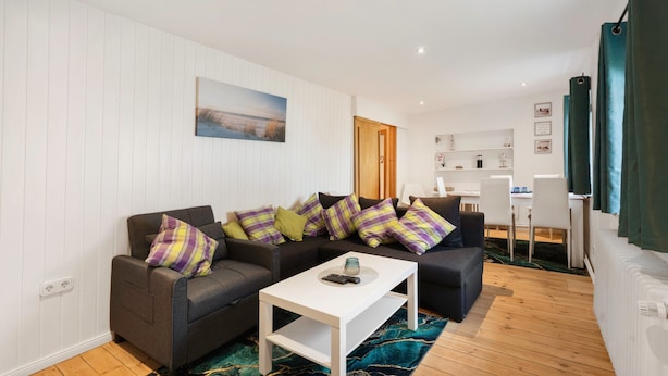 A modern living room with a sofa set, a coffee table, and a view of the kitchen area.