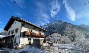 Un chalet con un balcone, una recinzione in legno e paesaggi innevati.