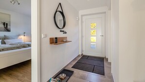 A hallway with a bed, a mirror, a shelf with a bowl, and a door with a window. - Apartment 'Ferienhaus Waterkant Mit Hund' with Private Terrace, Private Garden and Wi-Fi (Klanxbüll)