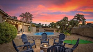 A backyard with a pool, chairs, a fire pit, and a golf putting green. - Desert Paradise Pool, Mini Golf, Fire Pit, Games, Relax and unwind (Phoenix)