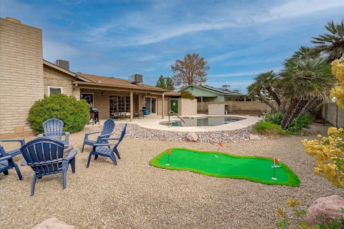 A backyard with a pool, a miniature golf course, and outdoor seating.