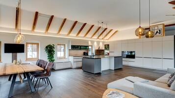 A modern kitchen with a central island, wooden beams on the ceiling, and pendant lighting.