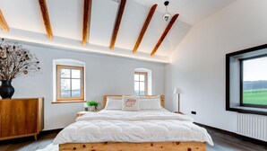 A bedroom with a wooden bed frame, two windows, a radiator, and a view of the outdoors. - Studio Apartment 'Außergewöhnliches Loft' with Mountain View and Wi-Fi (Senftenbach)