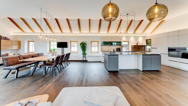 A modern kitchen with a central island, wooden beams on the ceiling, and pendant lighting. - Studio Apartment 'Außergewöhnliches Loft' with Mountain View and Wi-Fi (Senftenbach)
