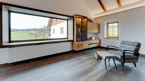 A room with a large window, wooden flooring, a built-in bookshelf, and a chair. - Studio Apartment 'Außergewöhnliches Loft' with Mountain View and Wi-Fi (Senftenbach)