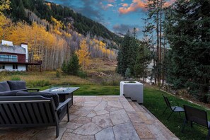 A patio with stone flooring, outdoor furniture, and a view of a forested hillside. - 6 Bedroom Riverside Haven in East Vail (Vail)