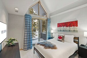 A bedroom with a bed, a window with curtains, a painting on the wall, and a plant on a table. - 6 Bedroom Riverside Haven in East Vail (Vail)