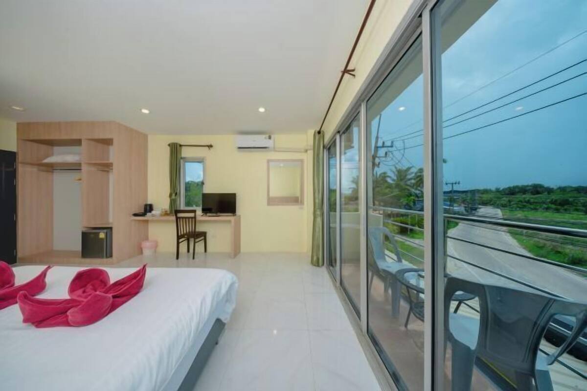 A modern hotel room with a bed, desk, and large sliding glass door to a balcony.