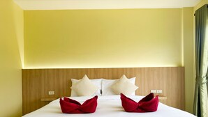 A hotel room with a bed, wooden headboard, and yellow walls. - Nan's Aonang (Krabi)