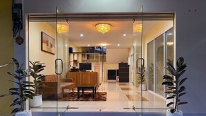 A modern entrance with a glass door, a red mat, and potted plants on either side. - Nan's Aonang (Krabi)