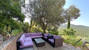 A sectional sofa set with a glass coffee table, positioned on a stone patio with a view of a mountainous landscape.