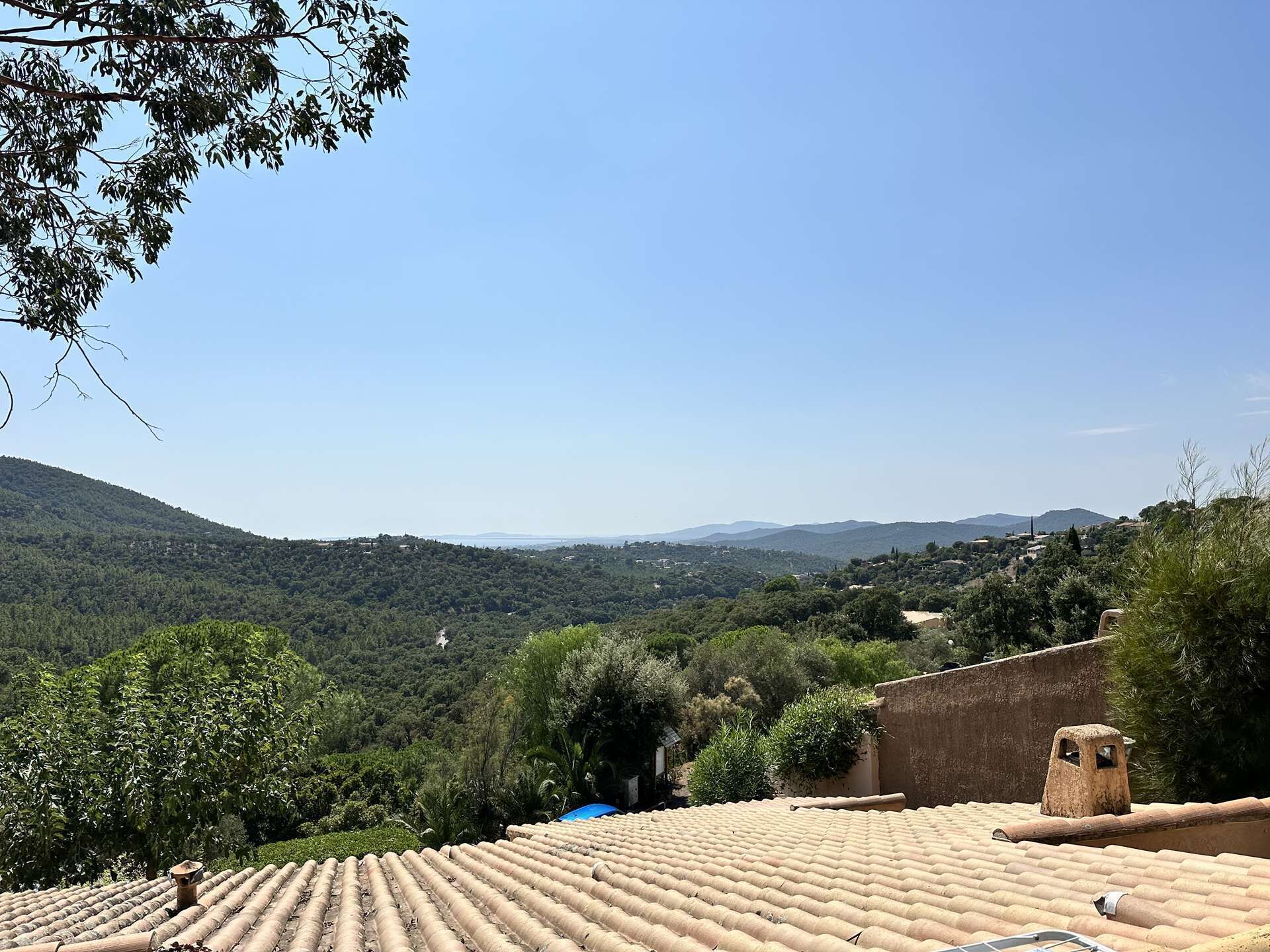 A terracotta-tiled roof with a view of a lush valley and distant hills.
