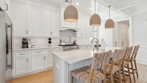 A modern kitchen with white cabinetry, a central island, and three hanging wicker pendant lights.