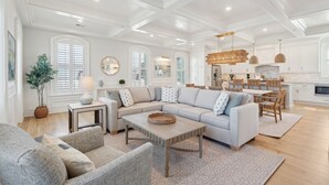A spacious living room with a sectional sofa, a coffee table, and a dining area with a chandelier.