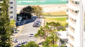 A high-rise building with a view of the ocean and a parking area.