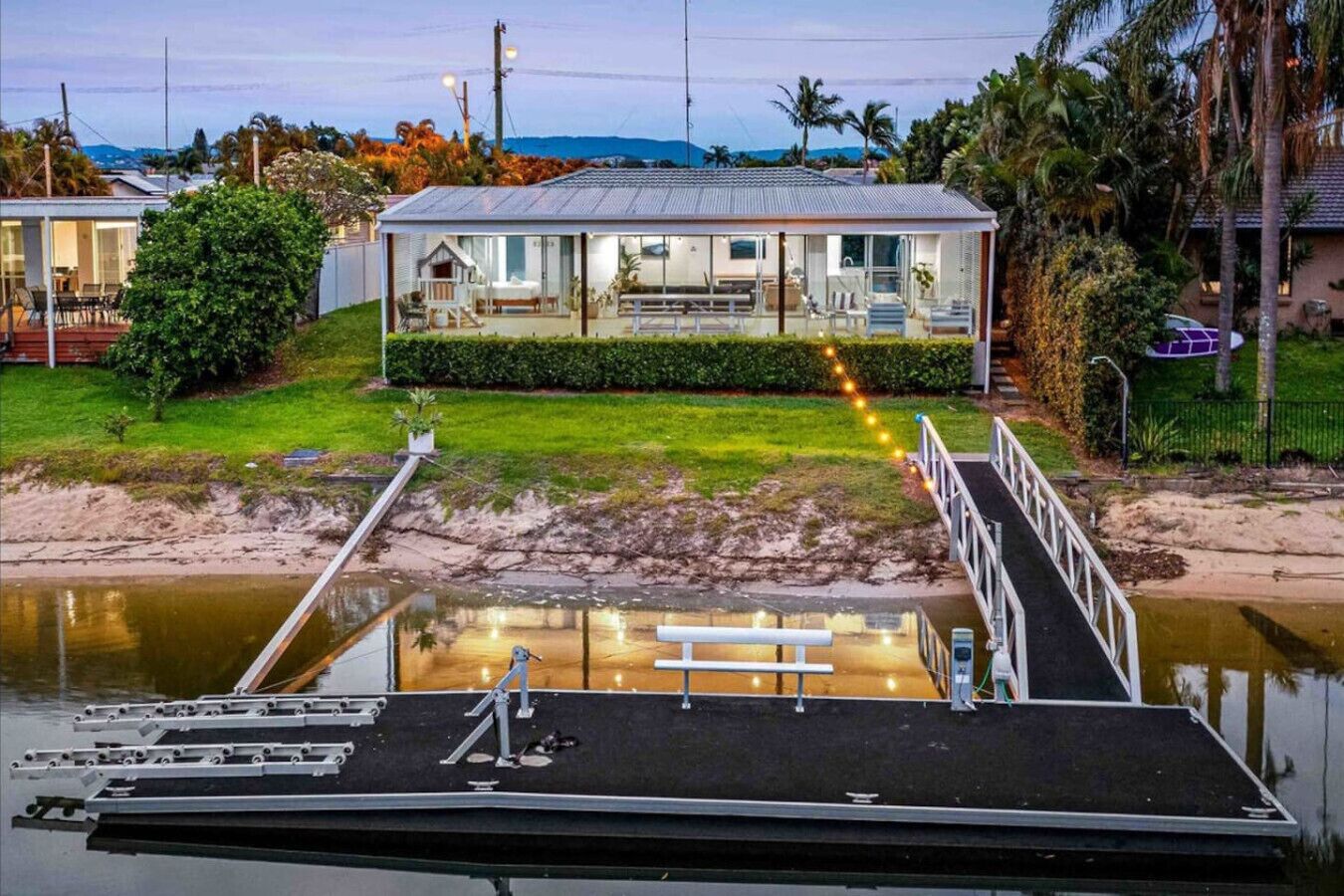 Una proprietà sul lungomare con un molo, una piccola casa con balcone e una zona verde.