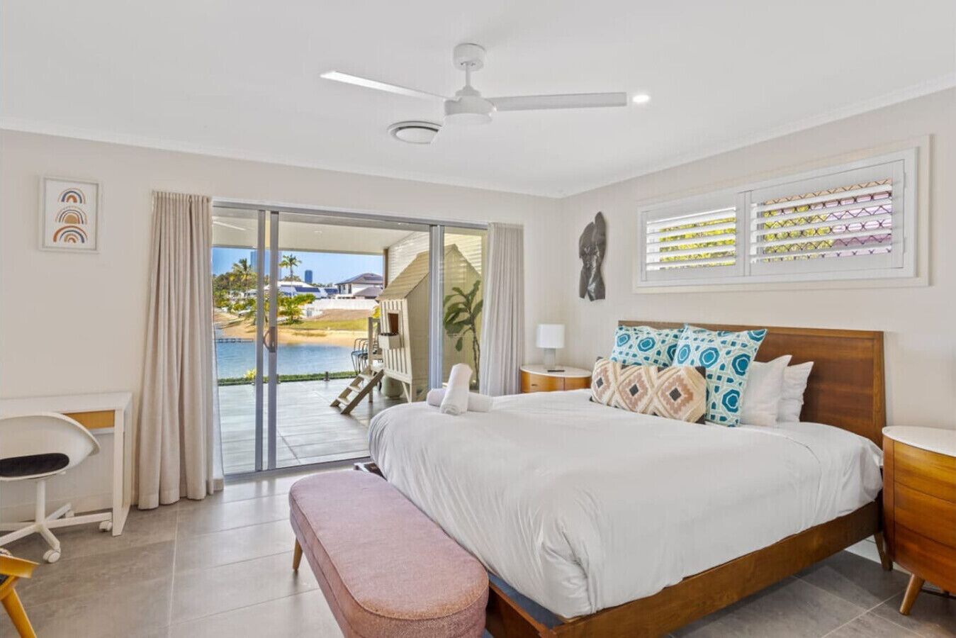 Camera da letto con un letto grande, una scrivania e una panca. Una porta scorrevole in vetro dà accesso a un balcone con vista sulla spiaggia e sull'oceano.