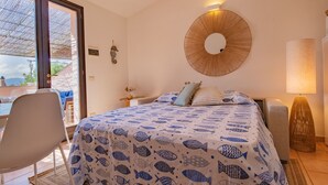 A bedroom with a bed, a chair, a lamp, and a wall-mounted mirror.