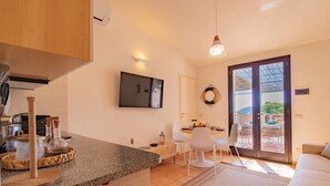 A modern kitchen with granite countertops, a dining area with white chairs, and a large sliding glass door leading to an outdoor patio.