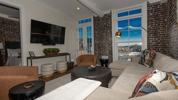 A modern living room with a large window, a flat-screen TV, and a city view.