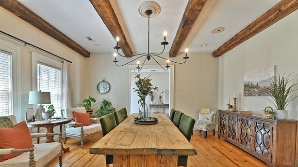 Un comedor con una mesa y sillas de madera, una araña y techo de madera.