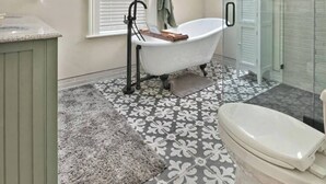 Un baño moderno con una bañera independiente, cabina de ducha de vidrio y tragaluz.