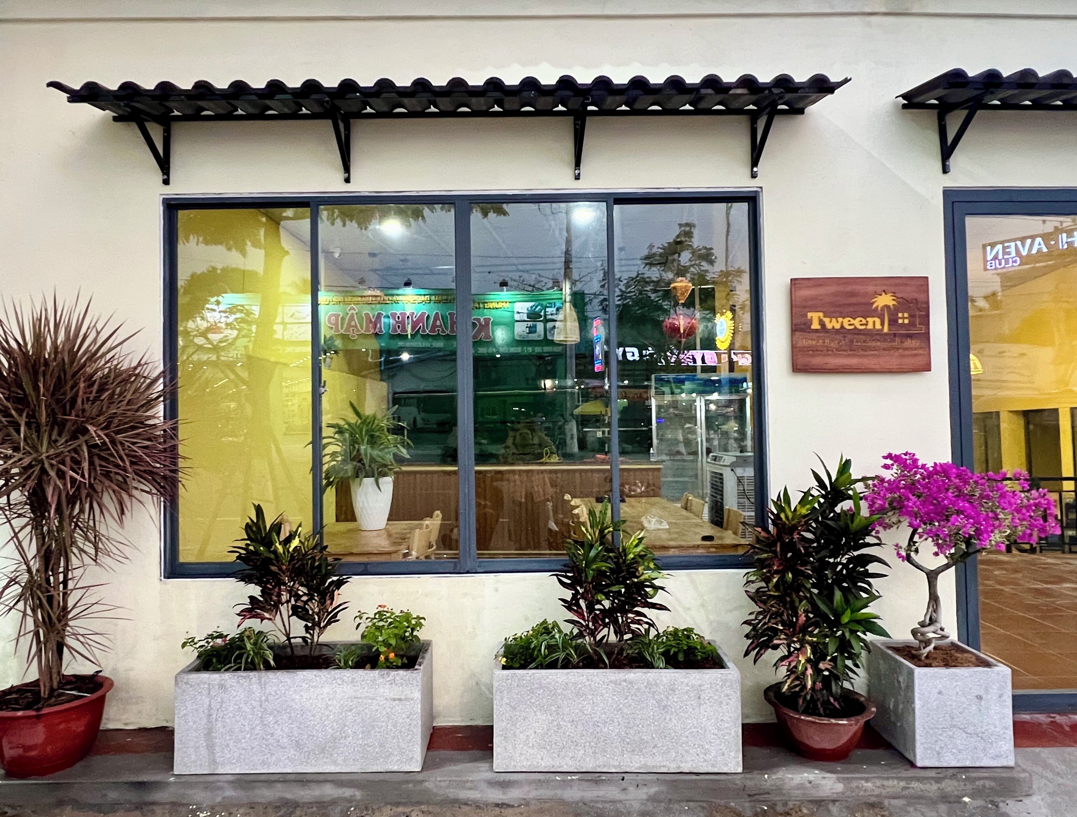 Un ristorante con un'ampia vetrata, piante in vaso e un cartello con scritto "Twen".