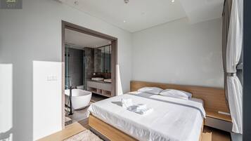 Una habitación de hotel moderna con una cama grande, un baño con bañera y vistas a la ciudad.