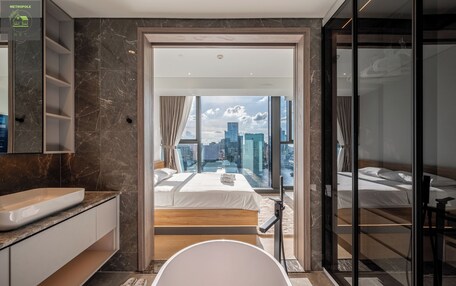 A modern hotel room with a large bed, a bathtub, and a city view.