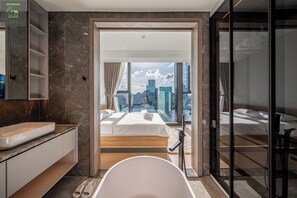 Une chambre d’hôtel moderne avec un grand lit, une baignoire et une vue sur la ville.