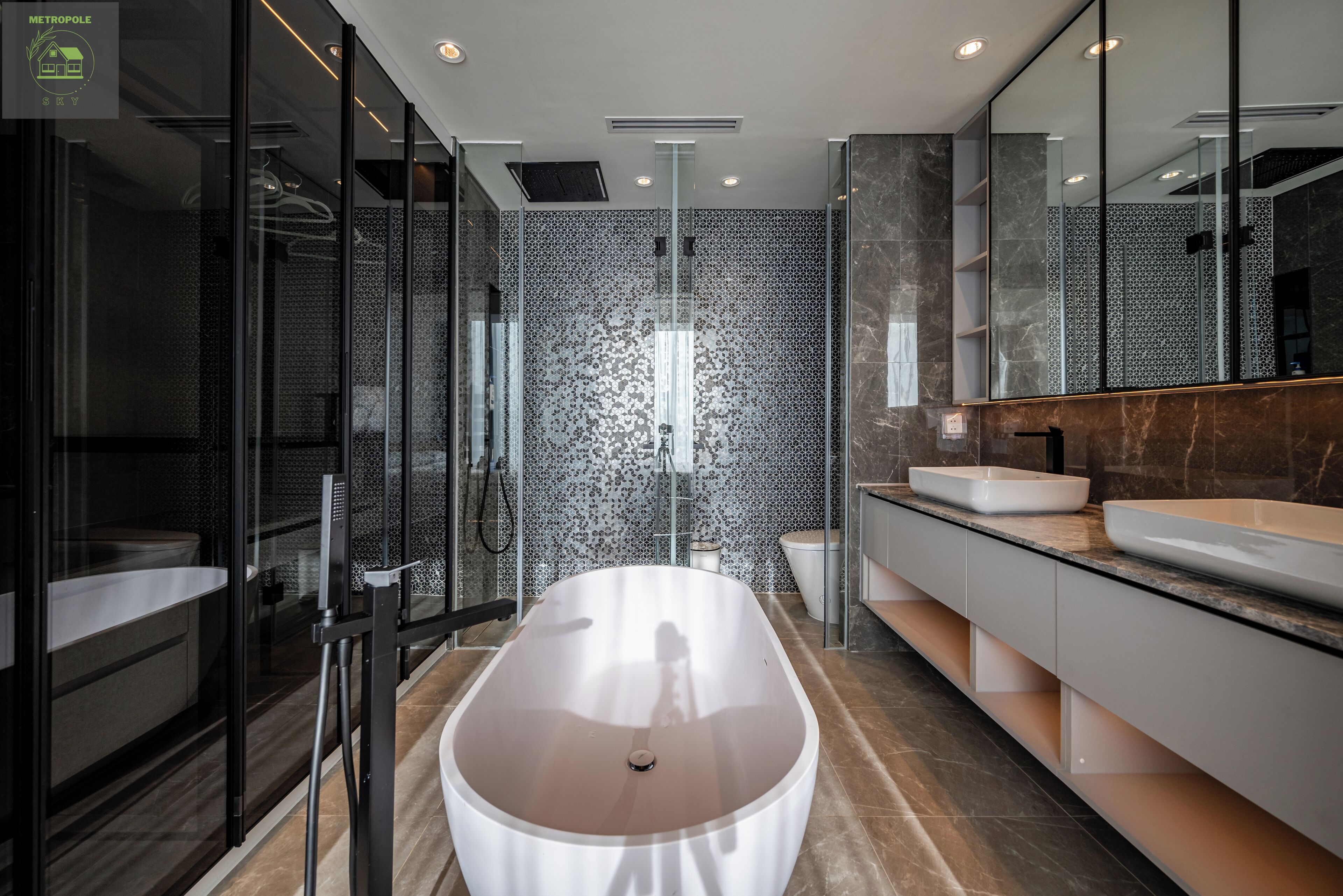 A modern bathroom with a freestanding bathtub, a glass shower enclosure, and a vanity with two sinks.