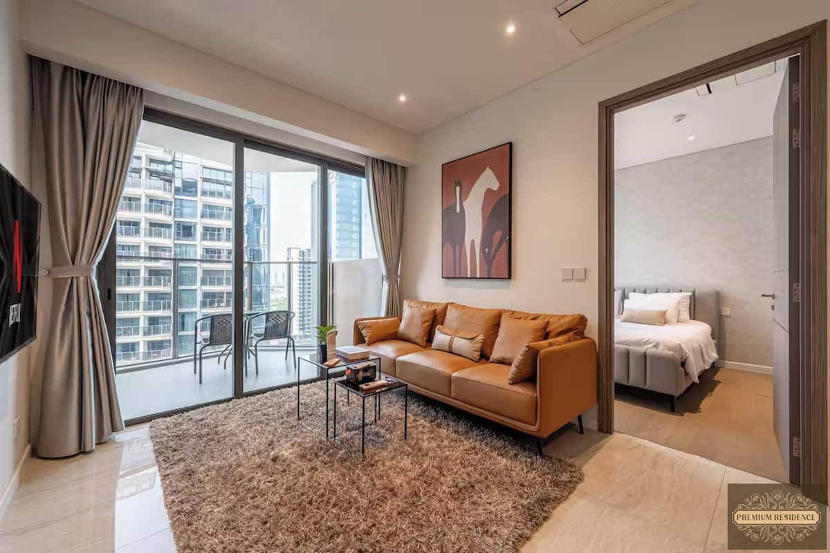 A modern living room with a large window, a sofa, a coffee table, and a view of a high-rise building.