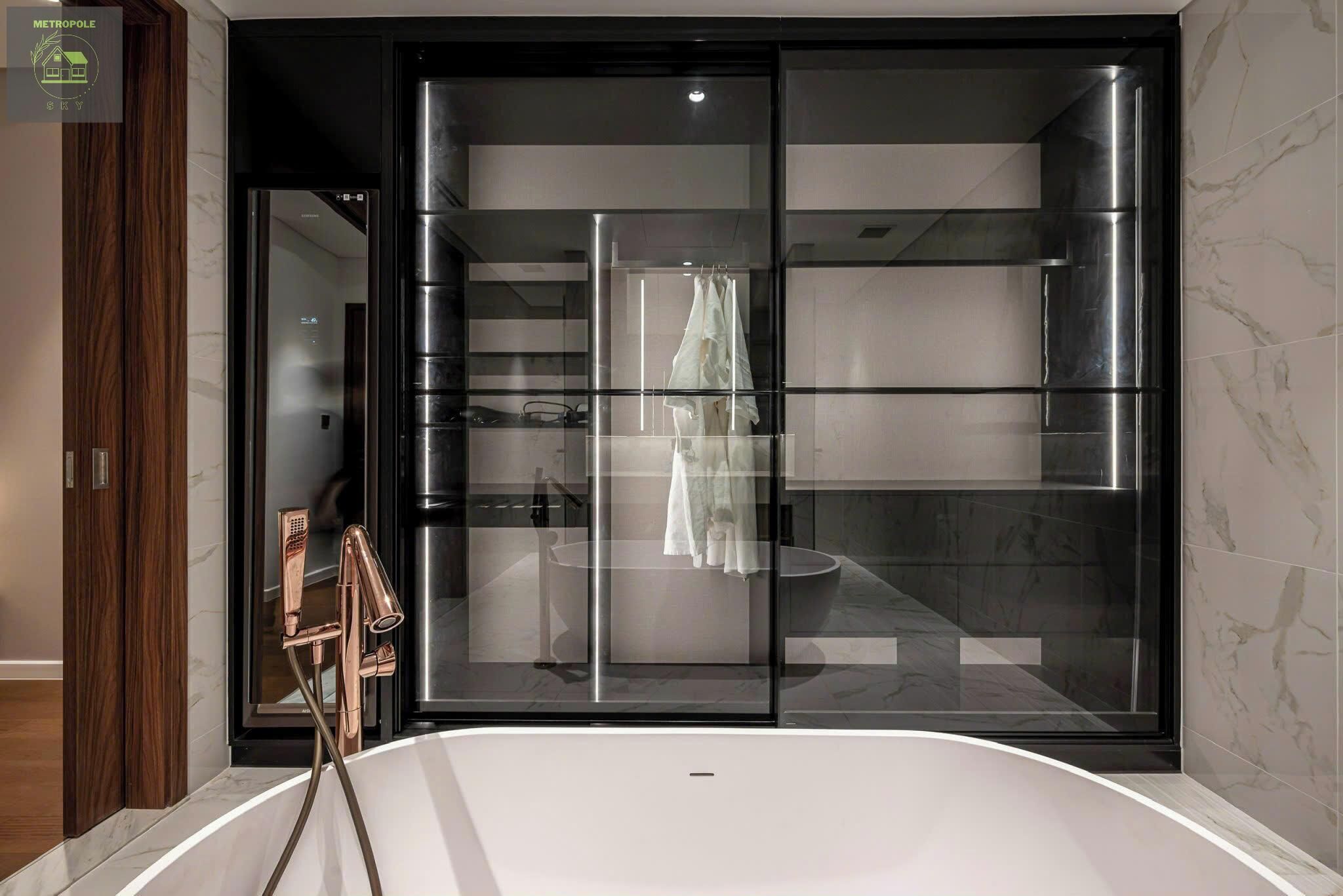 A modern bathroom with a glass-enclosed shower, a large bathtub, and a visible towel rack.