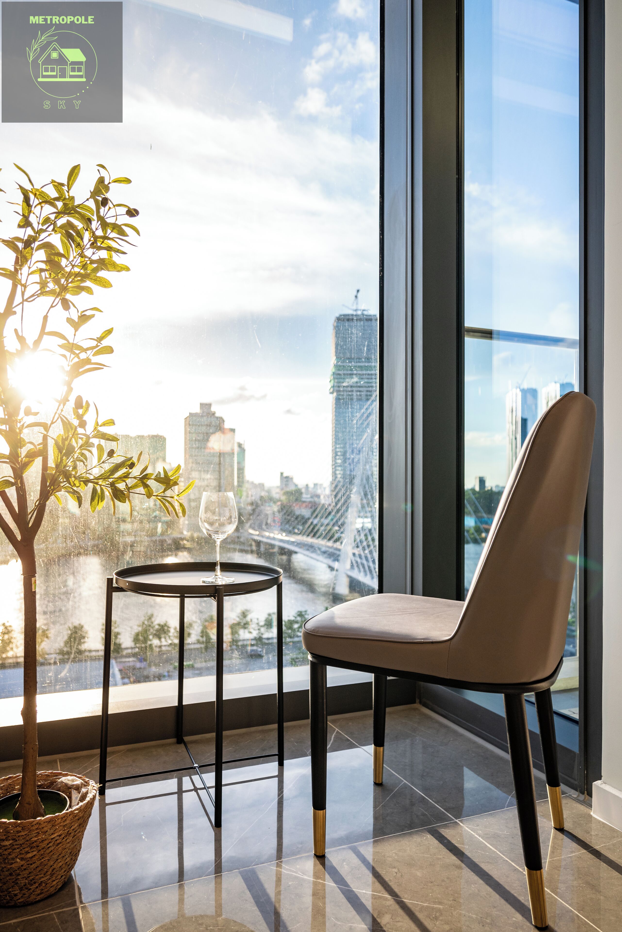 A modern room with a large window, a potted plant, a round table with a glass, and a chair.