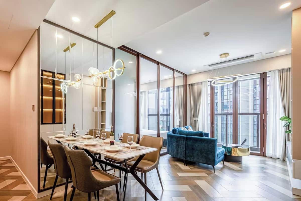 A modern dining area with a long table, chairs, and a blue sofa.