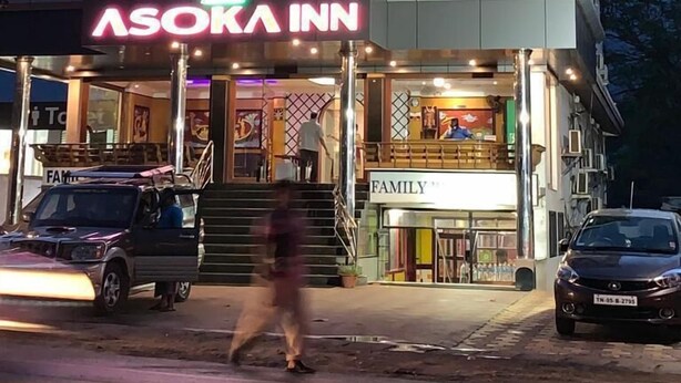 Egy többemeletes épület, amelyen feltűnő tábla hirdeti az Asoka Inn szállodát.