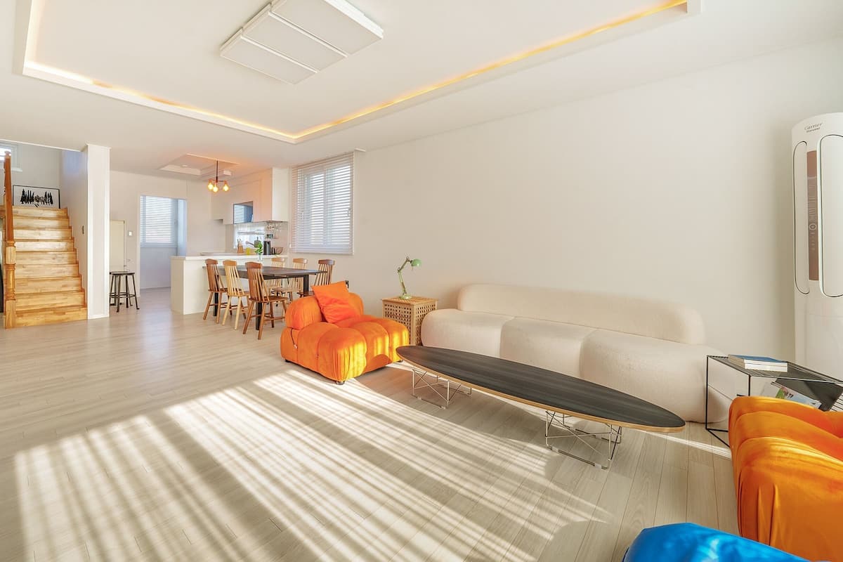 A modern living room with a sofa, a coffee table, and a dining area with chairs and a table.