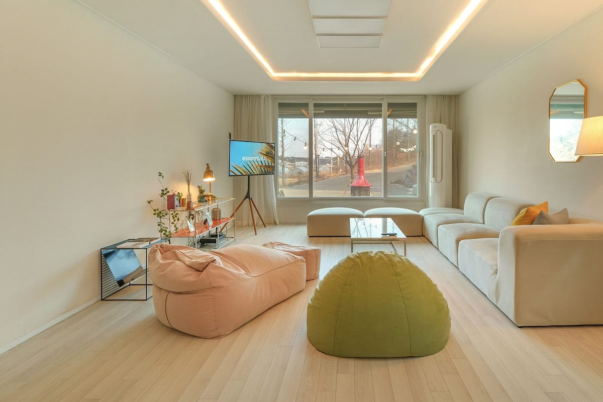 A modern living room with a sofa, a green bean bag, a coffee table, and a TV.
