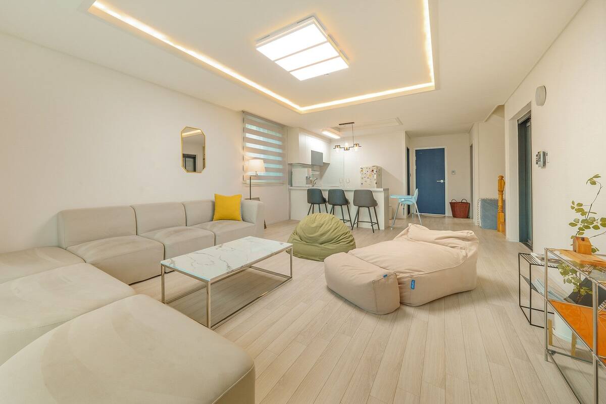 A modern living room with a sofa, ottoman, and a glass coffee table.