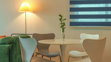 A dining area with a round table, chairs, a lamp, and a plant.