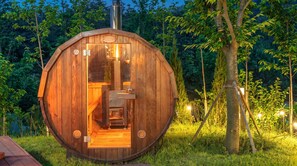 Una cabaña de madera con una puerta circular, una chimenea empotrada y un pequeño banco de madera en su interior.