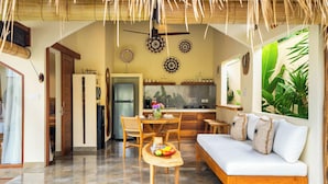 A spacious living area with a dining table, wooden chairs, a sofa, and a kitchen in the background. - Villa Aldona by Pertama Stay (Tabanan)