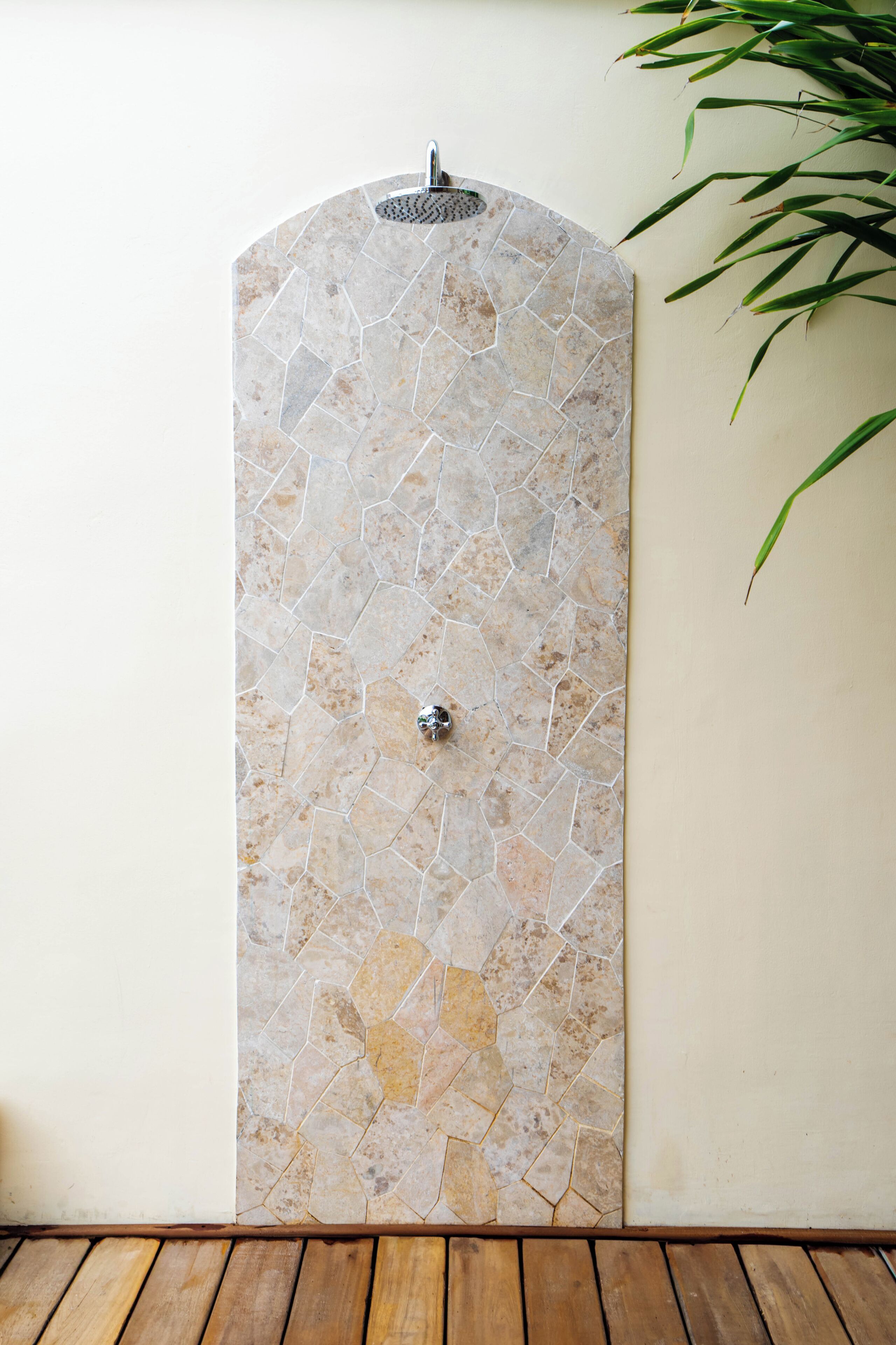 A shower area with a mosaic tile wall and a wooden floor.