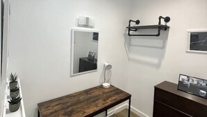 A modern room with a wooden desk, a chair, a dresser, and a wall-mounted shelf.
