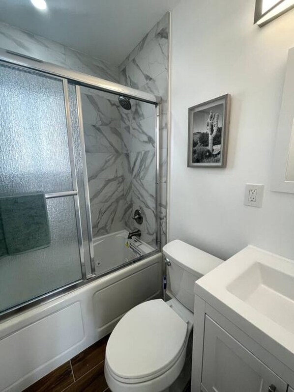 Un baño con ducha de mampara, inodoro y lavamanos.