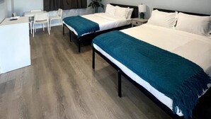 A hotel room with two beds, a desk, and a chair.